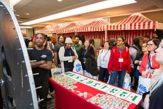 A group of paraprofessionals gather around a roulette table during the carnival at the 2024 UFT Paraprofessional Festival and Awards Luncheon