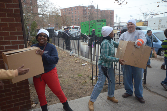UFT Vice President Janella Hinds (left), Brooklyn HS for Public Service secretary Sherma Owens and UFT President Michael Mulgrew are part of a chain delivering supplies. (Miller Photography)
