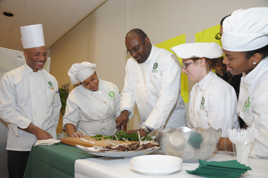 UFT Vice President Sterling Roberson (center) gets a lesson in chopping under the watchful eyes of Chapter Leader Geoffrey “Chef Geoff” Tulloch (left) and culinary arts students at Food and Finance HS in Manhattan. (Miller Photography)
