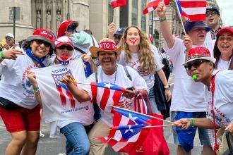 A group of people smile while wearing Puerto Rican flag colored clothing