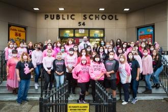 A group photo of staff at a public school in Staten Island. Most are wearing breast cancer awareness masks.