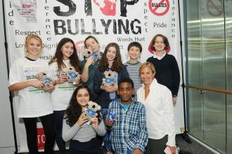Group of students with teacher in front of sign that says STOP BULLYING