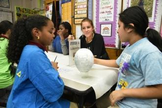 Two girls in foreground painting white orb, UFT teacher in background - professional development
