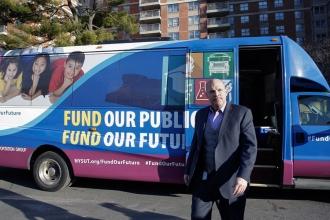 Man walks in front of bus that reads Fund Our Public Schools