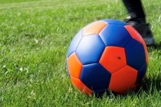 A blue and orange soccer ball on green grass 
