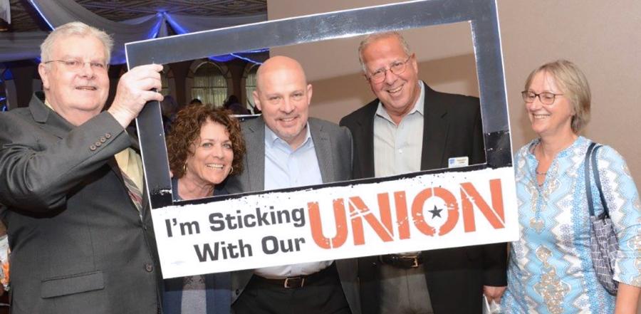 People pose behind cutout that says, "I'm sticking with our Union"