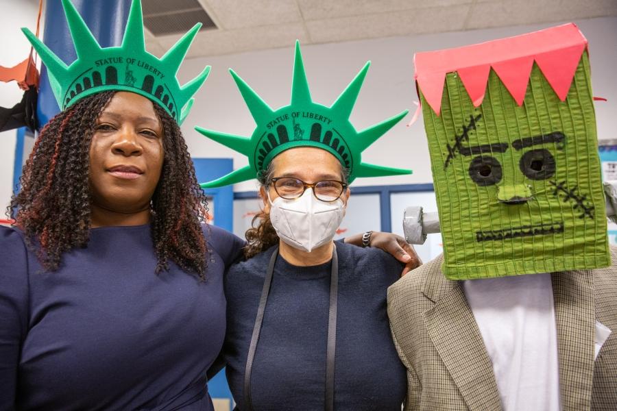 Two women wearing Statue of Liberty crowns stand next to someone wearing a homemade Frankenstein 