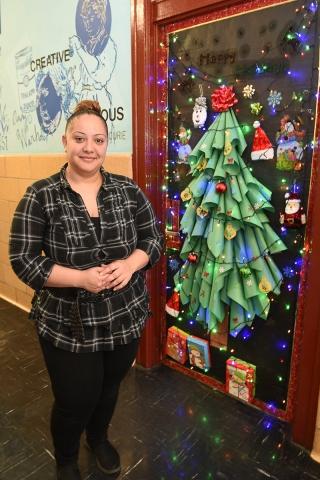 Woman stands in front of a door decorated as a Christmas tree