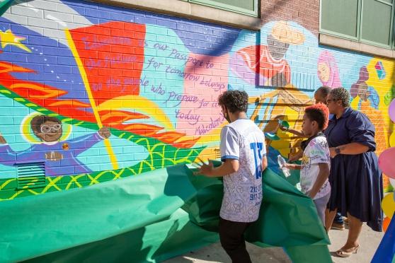 With help from Principal Anjelica Jordan, student artists unveil the mural to reveal the Malcolm X quote they helped select.