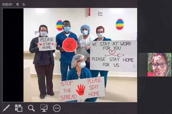 Nurses attend a video call while posing and holding up signs