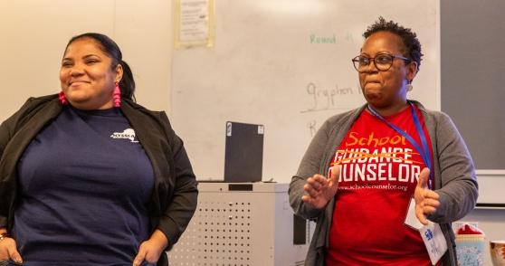 A school counselor on the right leads members in a workshop on ideas to engage students
