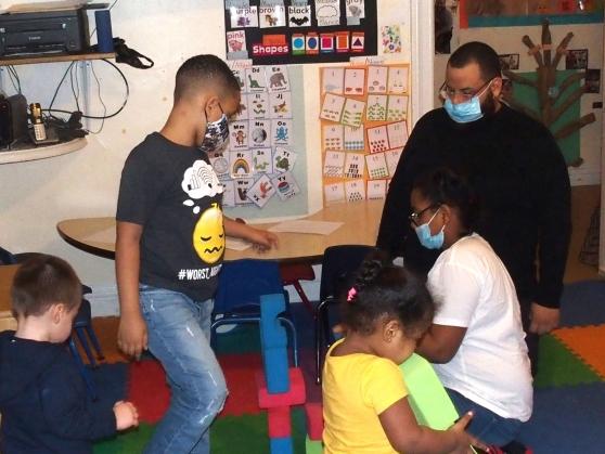 Students interact with a child care provider at a day care