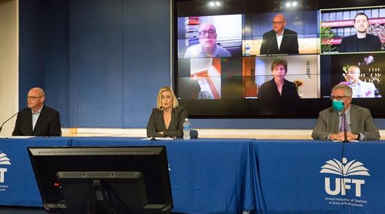 Three UFT officials speaking at a press conference podium