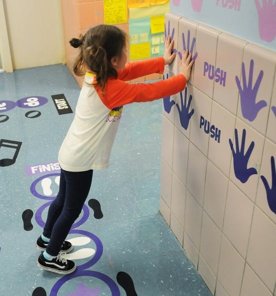 child presses against a school building wall with handprints and the word 'push'