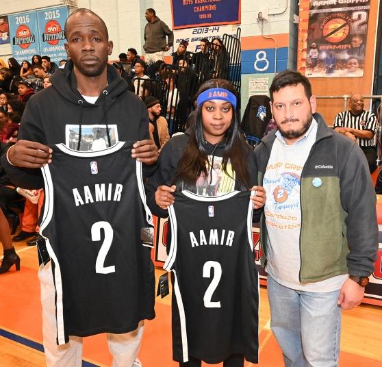 UFT Queens High Schools District Representative James Vasquez (right) with Aamir’s parents, holding jerseys dedicated to Aamir by the Brooklyn Nets.