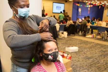  Adult education coach Jose Jean works on a student’s hair
