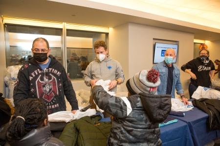  UFT Vice President for Middle Schools Richard Mantell (second from right) helps give children their new coats and goodie bags