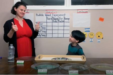 Woman and child in front of a chart that says Bubble Wand Experiment