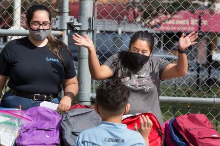 School aide Elisole Compres (left) and social worker Estephanie Pachucho welcome a student to a school supplies giveaway on Sept. 26, three days before classes began at PS 329 in Queens.