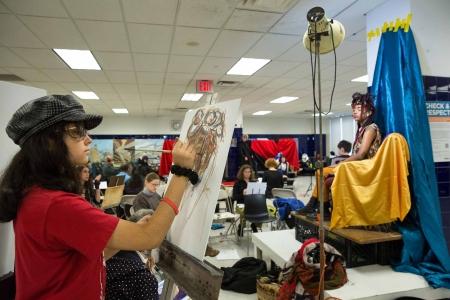A student paints a portrait of a model in costume