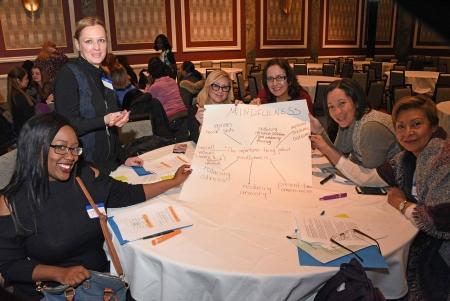 Table of paraprofessionals holding chart paper