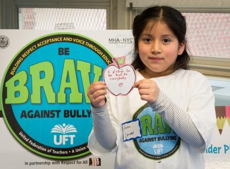 A student holding up a message in front of a BRAVE poster