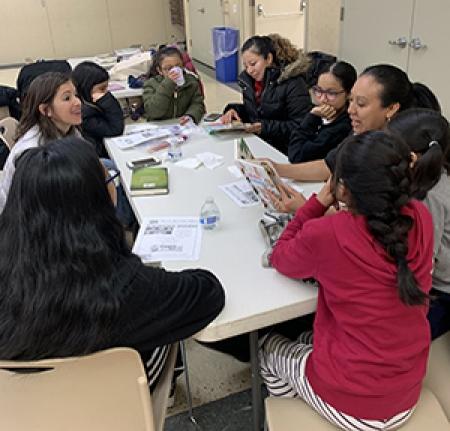 A woman reads to a group of children sitting at a table.