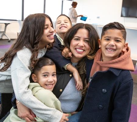 A parent in attendance takes a photo with her children at the UFT Queens Parent Summit on Nov. 23, 2024