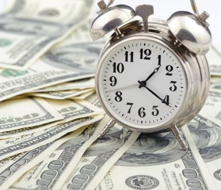 Clock on a surface full of $100 bills