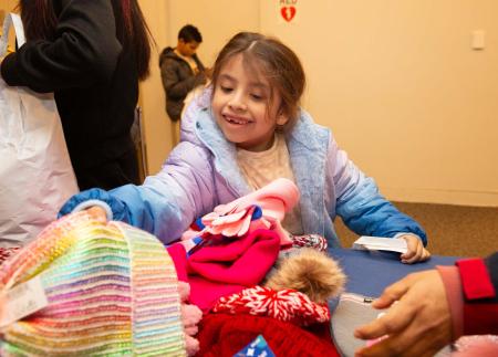 A young student smiles while getting to pick out winter attire 
