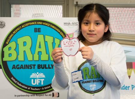A student holding up a message in front of a BRAVE poster