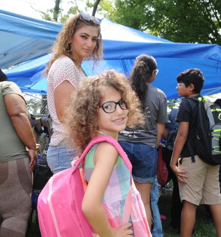 A student shows off her backpack as her parent looks on