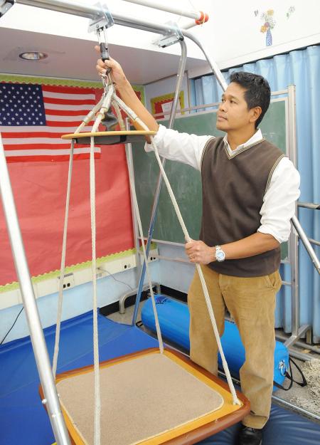 A man stands with a wheelchair lift in a classroom.