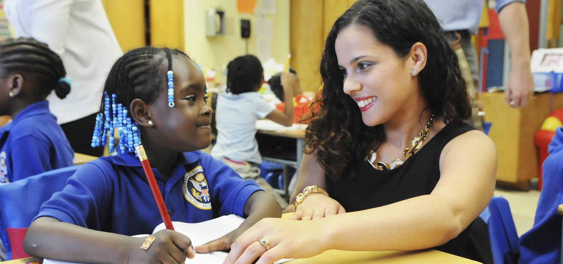 UFT teacher with curly brown hair gazing at African-American student