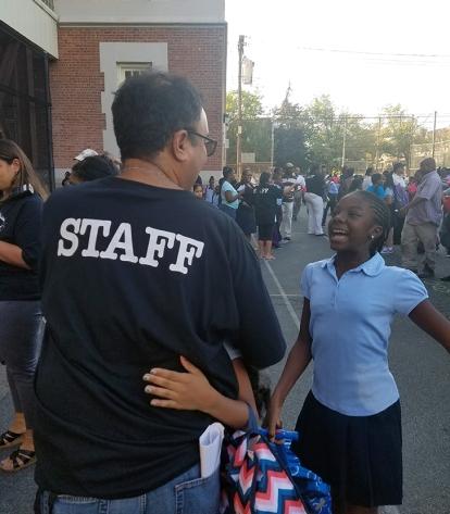 A teacher at PS 115 in Canarsie, Broooklyn, welcomes two returning students on o
