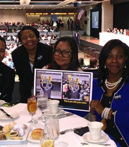 parent activists seated at a table in a crowded hall holding up a brochure