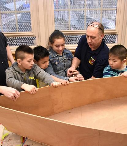 Heinz shows his boatbuilders how to fasten zip ties with McKeown’s help.