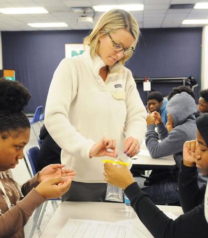Teacher Christine Hunkele (center) helps students measure the quality of a water
