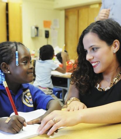 UFT teacher with curly brown hair gazing at African-American student
