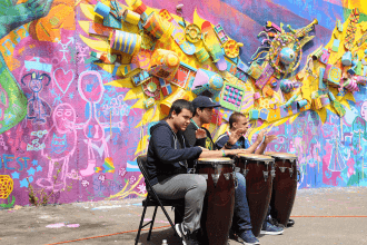 Three students from 751M play the drums to energize the audience during the cere