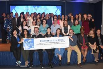 Large crowd poses for the camera holding up award banner that recognizes the HS