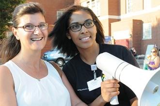 Resource coordinator Savanity Davis (right) uses a bullhorn to guide parents and