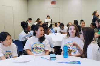 Female teacher and three girls sit at table talking