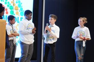 Kids on stage while one takes the mic