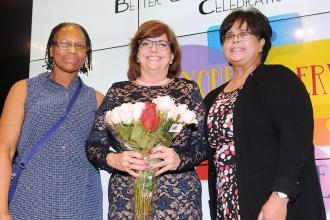 Event co-chairs Katherine Lewis (left) and Brenda Caquias present fl owers to Bo