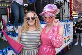 Women poses with a drag artist wearing pink sequins