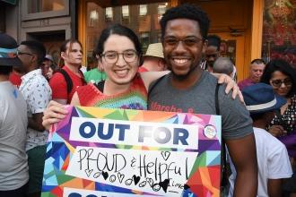 Two people pose with sign 'Out for Proud and Helpful Schools'