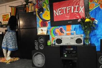 The entertainment center is next to the kitchen where someone is washing the dis