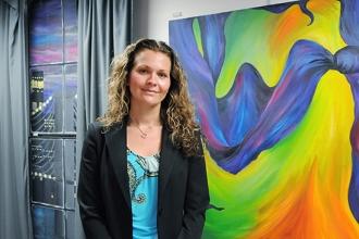 Susan Tuthill stands by a student painting created for the apartment and the fau