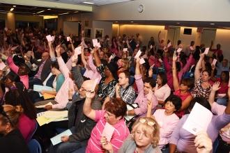 Delegates hold up on their pink cards to approve a resolution.